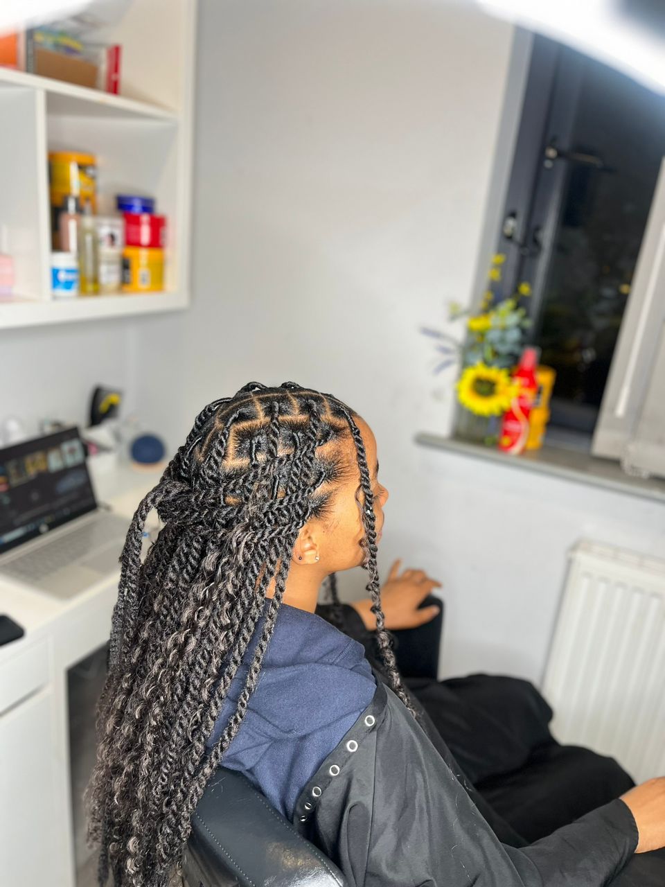 Long knotless braids with curly ends, part-finished in the studio chair.